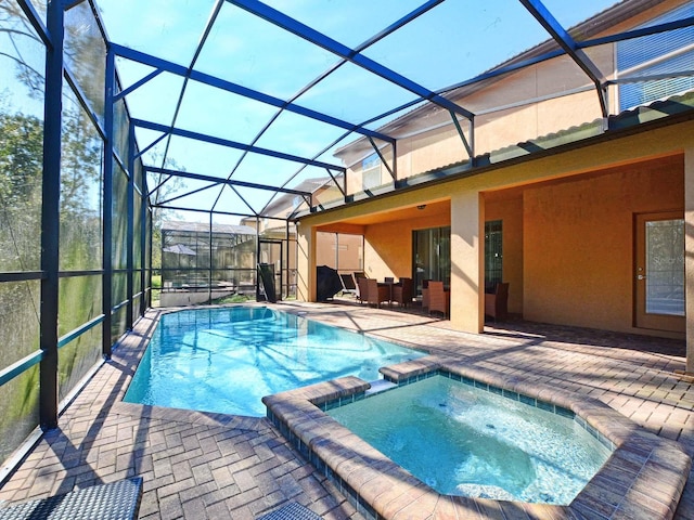 view of swimming pool featuring an in ground hot tub, a patio, and glass enclosure