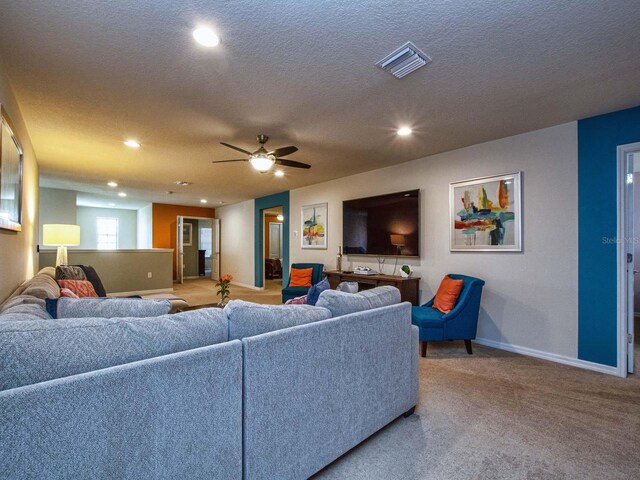 carpeted living room featuring a textured ceiling and ceiling fan