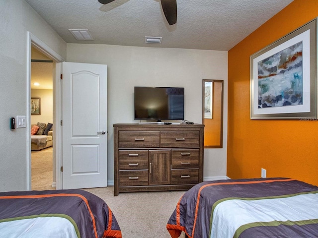 bedroom featuring light carpet, ceiling fan, and a textured ceiling