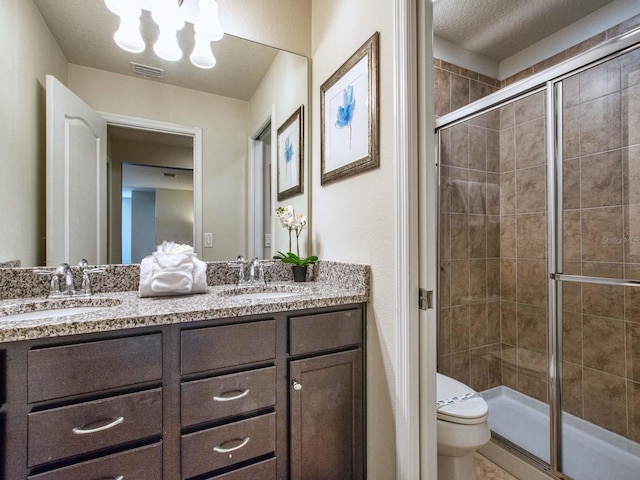 bathroom with walk in shower, a textured ceiling, toilet, and dual bowl vanity