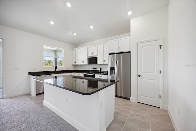 kitchen featuring stainless steel appliances, dark countertops, a center island, and white cabinets