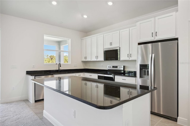 kitchen with white cabinets, dark countertops, a kitchen island, stainless steel appliances, and a sink