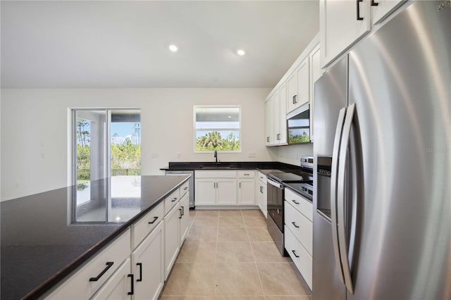 kitchen featuring appliances with stainless steel finishes, white cabinetry, a sink, and light tile patterned floors