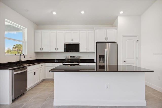 kitchen featuring appliances with stainless steel finishes, white cabinetry, a kitchen island, and a sink