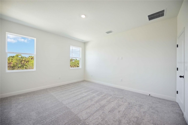 carpeted empty room with baseboards, visible vents, and recessed lighting