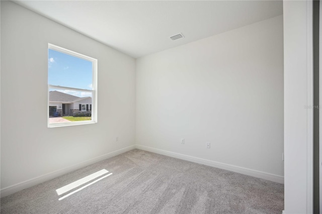 unfurnished room with light carpet, visible vents, and baseboards