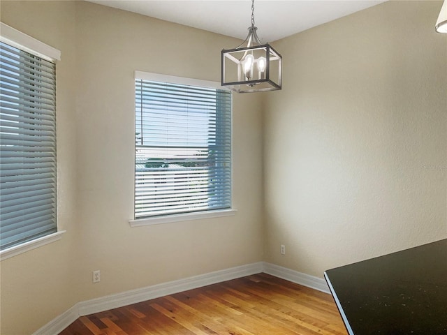 unfurnished dining area with wood-type flooring and an inviting chandelier