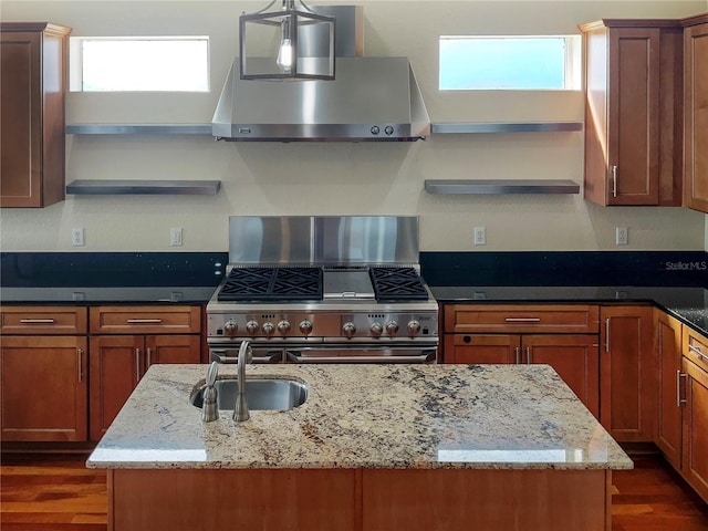 kitchen with sink, light stone counters, stainless steel range oven, range hood, and decorative light fixtures