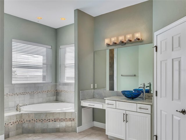 bathroom with tile patterned flooring, vanity, and a relaxing tiled tub