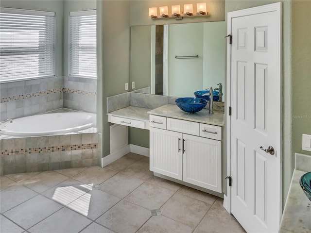 bathroom featuring tile patterned floors, vanity, and a relaxing tiled tub