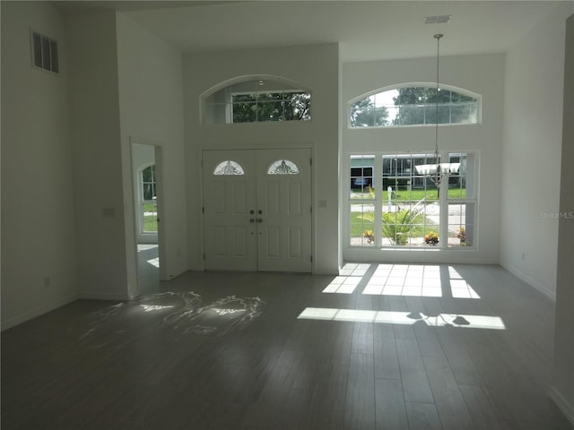 foyer with dark hardwood / wood-style floors, a chandelier, and a high ceiling