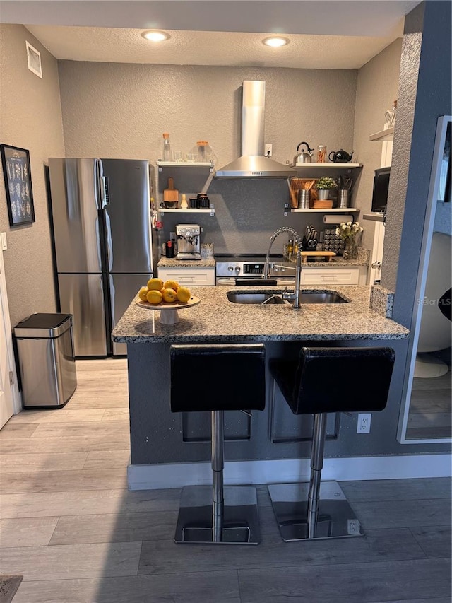 kitchen with extractor fan, a breakfast bar, stone counters, and appliances with stainless steel finishes