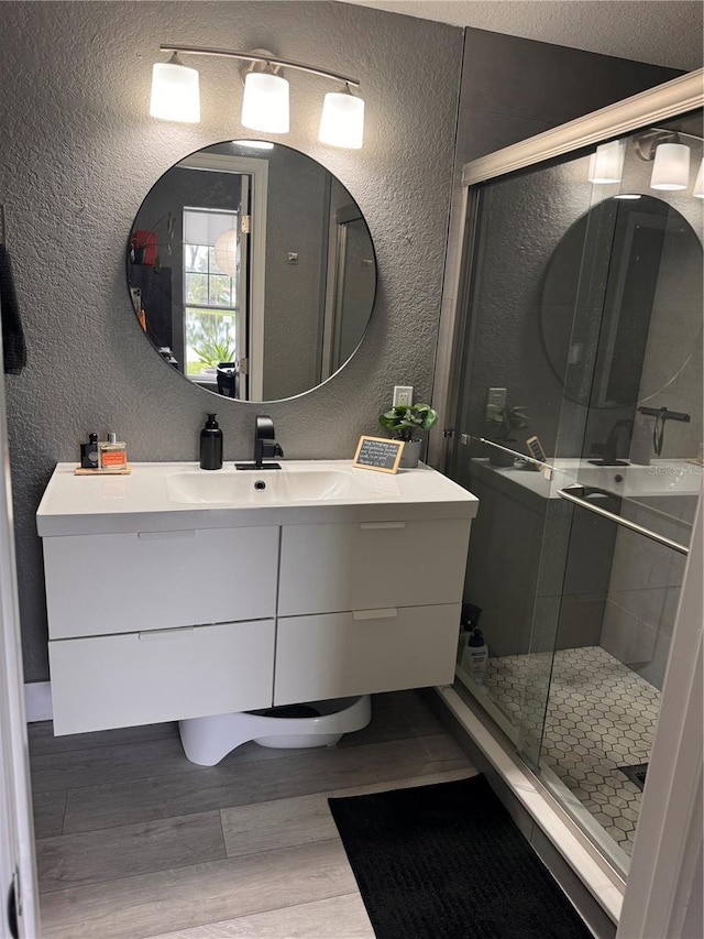 bathroom featuring vanity, hardwood / wood-style floors, a textured ceiling, and a shower with shower door