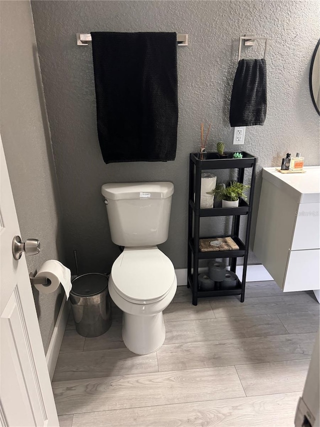 bathroom with hardwood / wood-style flooring, vanity, and toilet