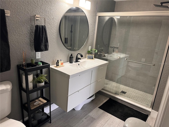 bathroom with vanity, wood-type flooring, a shower with shower door, and toilet