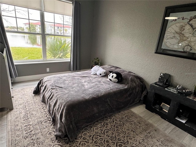 bedroom featuring light hardwood / wood-style floors and a water view