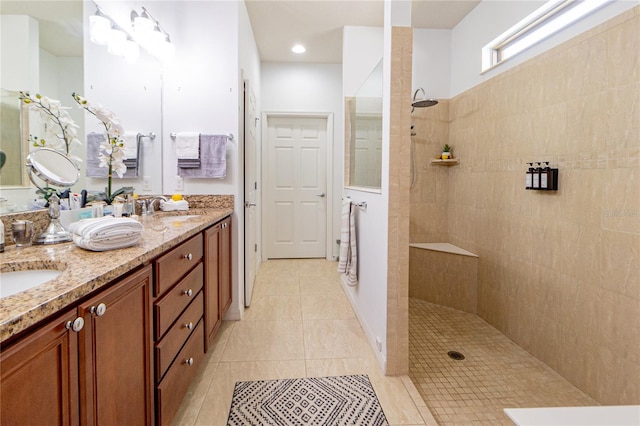 bathroom with tile patterned flooring, a tile shower, and vanity