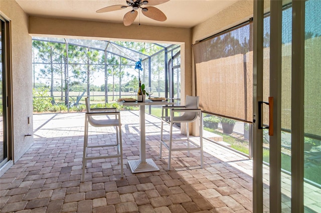 unfurnished sunroom featuring ceiling fan and plenty of natural light