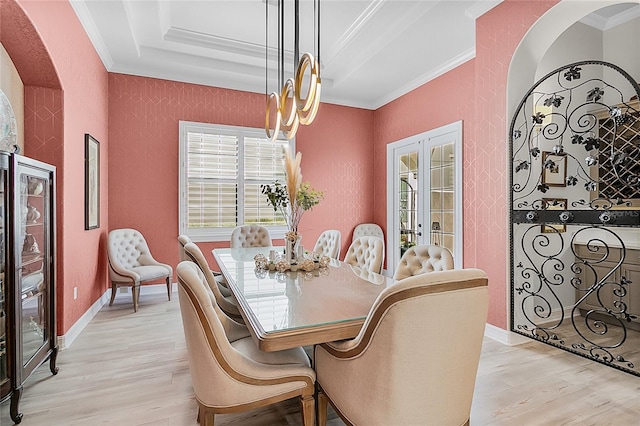 dining area with french doors, a raised ceiling, crown molding, and light hardwood / wood-style flooring