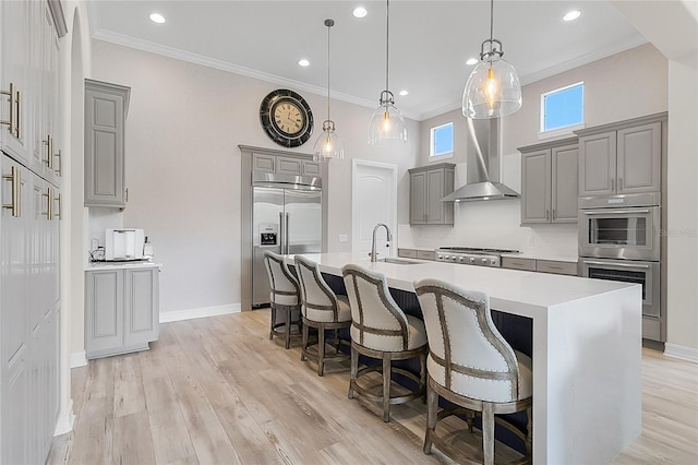 kitchen featuring hanging light fixtures, an island with sink, stainless steel appliances, and light hardwood / wood-style floors