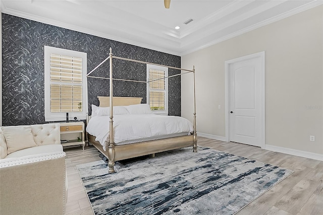 bedroom with ceiling fan, wood-type flooring, and a tray ceiling