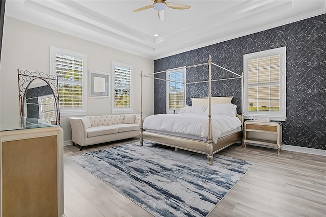 bedroom featuring a tray ceiling, light wood-type flooring, ornamental molding, and ceiling fan