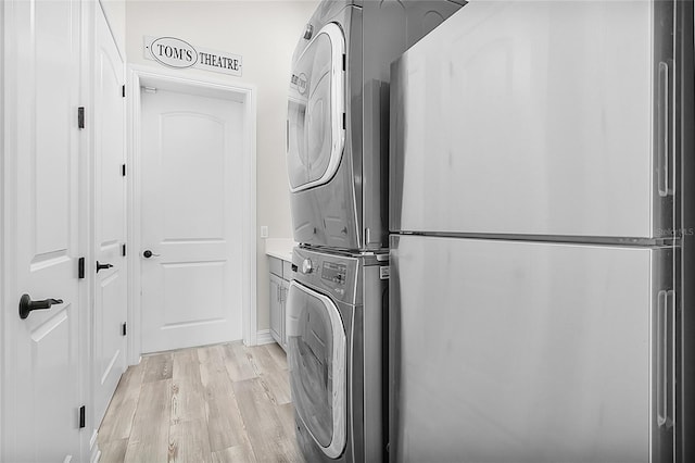 laundry room featuring light hardwood / wood-style flooring, cabinets, and stacked washer / dryer