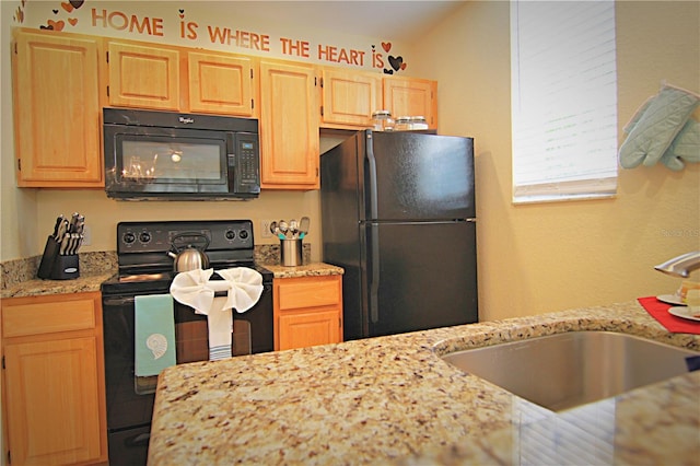 kitchen with light stone countertops, light brown cabinetry, sink, and black appliances