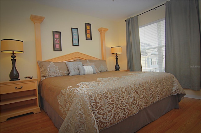 bedroom with hardwood / wood-style floors and ornate columns