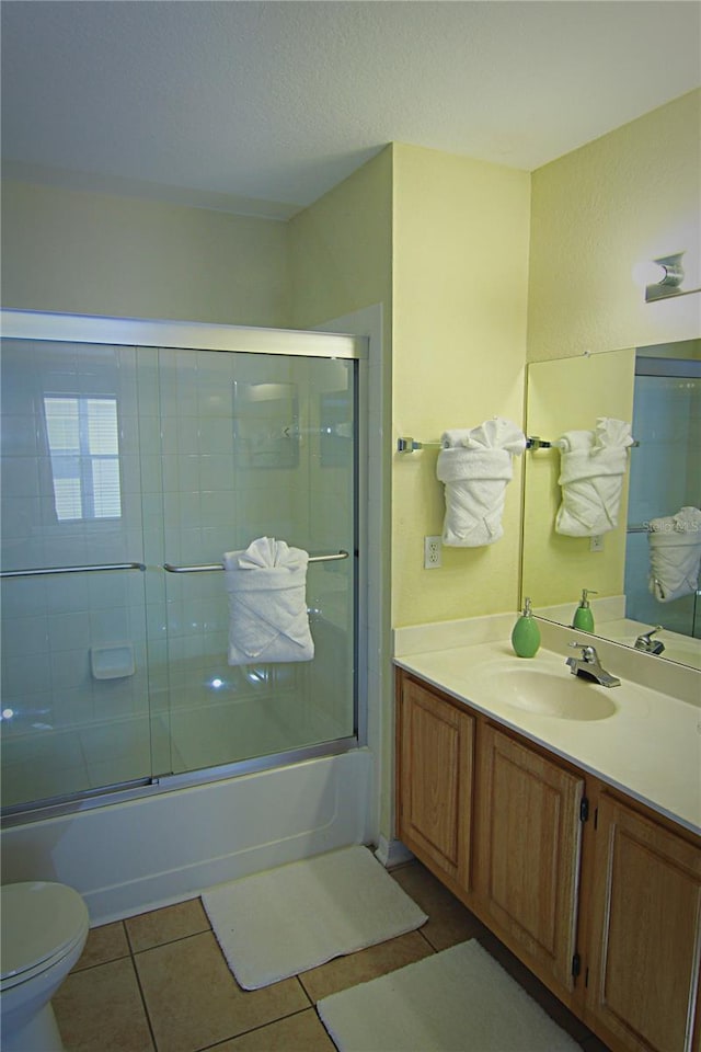 full bathroom featuring tile patterned floors, vanity, toilet, and enclosed tub / shower combo