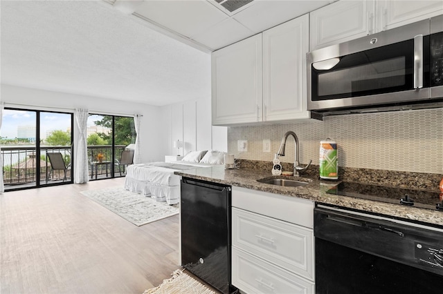 kitchen with dark stone countertops, black appliances, sink, and white cabinets