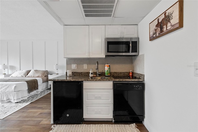 kitchen with sink, refrigerator, dark stone countertops, black dishwasher, and white cabinets