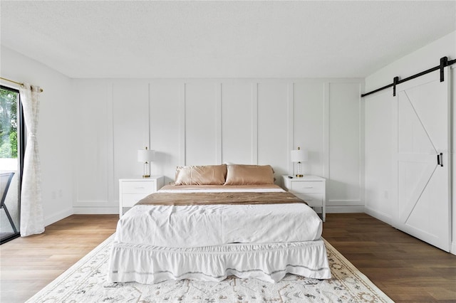 bedroom featuring a barn door and light hardwood / wood-style flooring