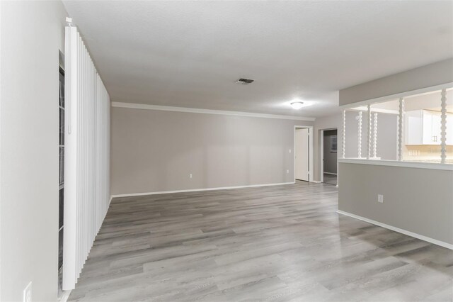 spare room featuring light hardwood / wood-style floors and crown molding