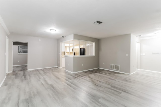 unfurnished living room featuring ornamental molding and light wood-type flooring