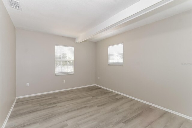 spare room with beamed ceiling and hardwood / wood-style flooring