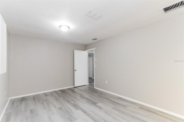 empty room with a textured ceiling and light wood-type flooring