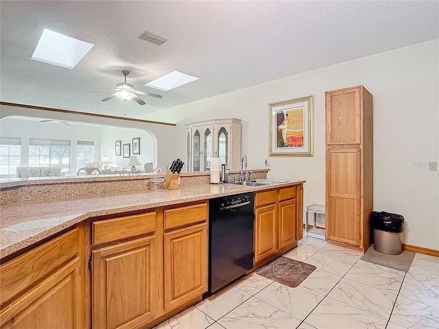 kitchen with sink, light stone counters, a skylight, a textured ceiling, and dishwasher