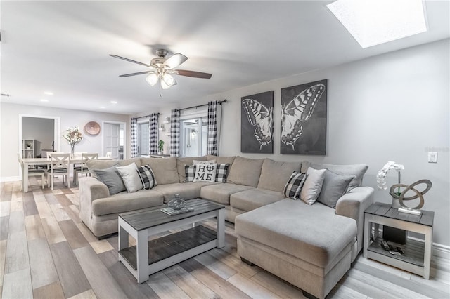 living room with a skylight, hardwood / wood-style floors, and ceiling fan