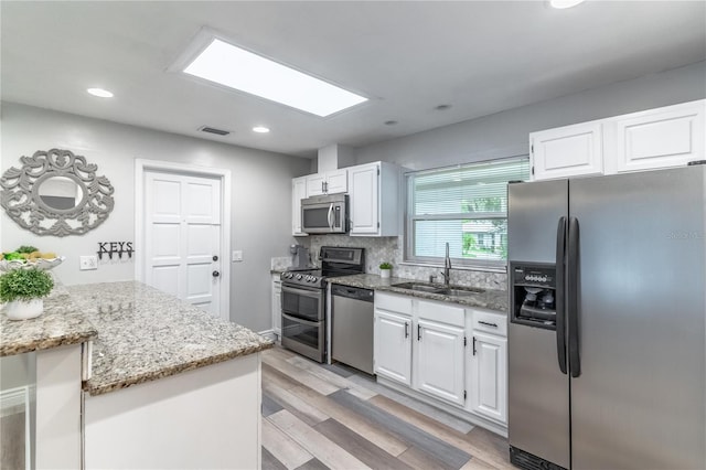 kitchen with white cabinets, light stone countertops, appliances with stainless steel finishes, and sink