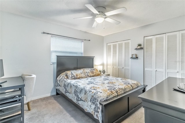 carpeted bedroom featuring multiple closets and ceiling fan