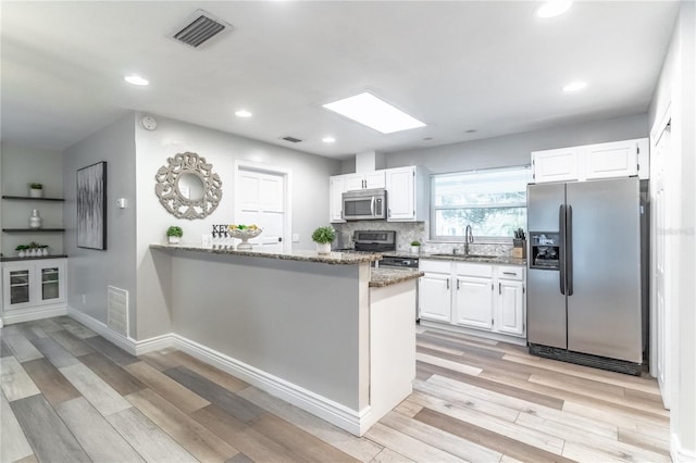 kitchen featuring light wood-type flooring, stainless steel appliances, stone countertops, and white cabinets