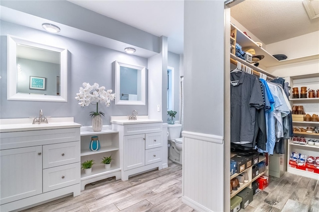 bathroom with hardwood / wood-style flooring, double sink vanity, and toilet