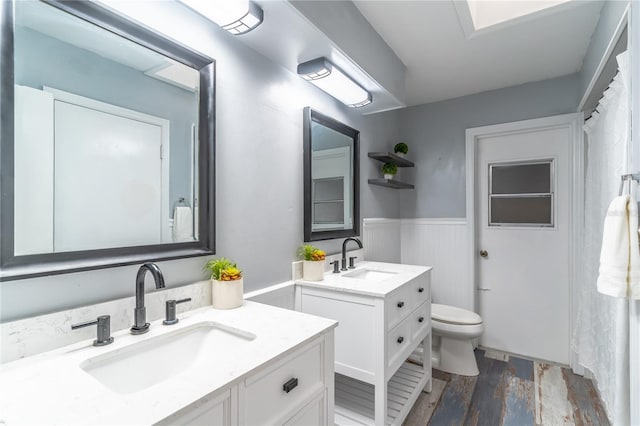 bathroom with toilet, hardwood / wood-style floors, and dual bowl vanity