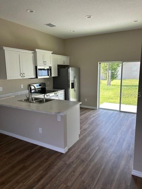 kitchen featuring a textured ceiling, stainless steel appliances, dark hardwood / wood-style flooring, white cabinets, and sink