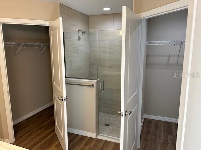 bathroom with a shower with door and wood-type flooring