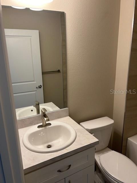 bathroom featuring toilet, vanity, and a tub