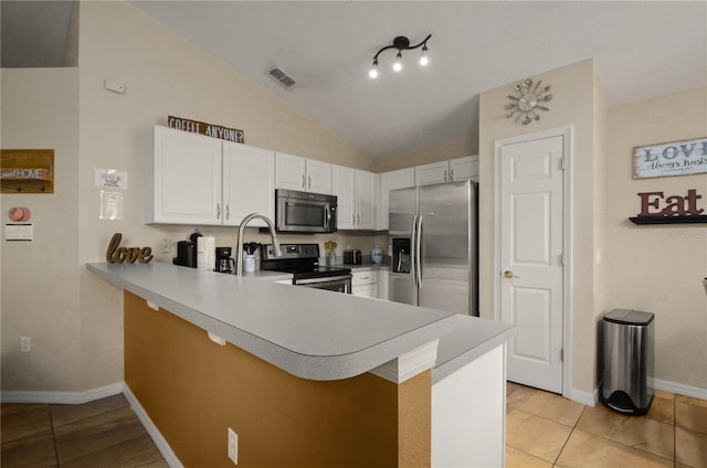 kitchen with track lighting, kitchen peninsula, vaulted ceiling, and stainless steel appliances