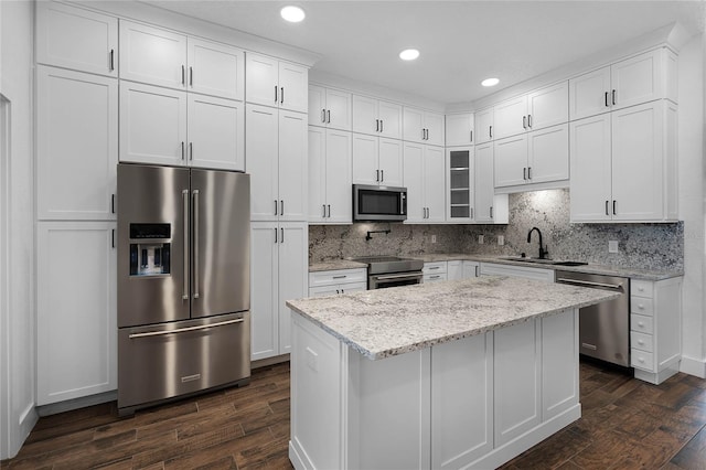 kitchen with dark hardwood / wood-style flooring, light stone counters, white cabinetry, and appliances with stainless steel finishes