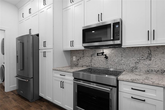 kitchen with white cabinetry, stacked washing maching and dryer, stainless steel appliances, and dark hardwood / wood-style floors